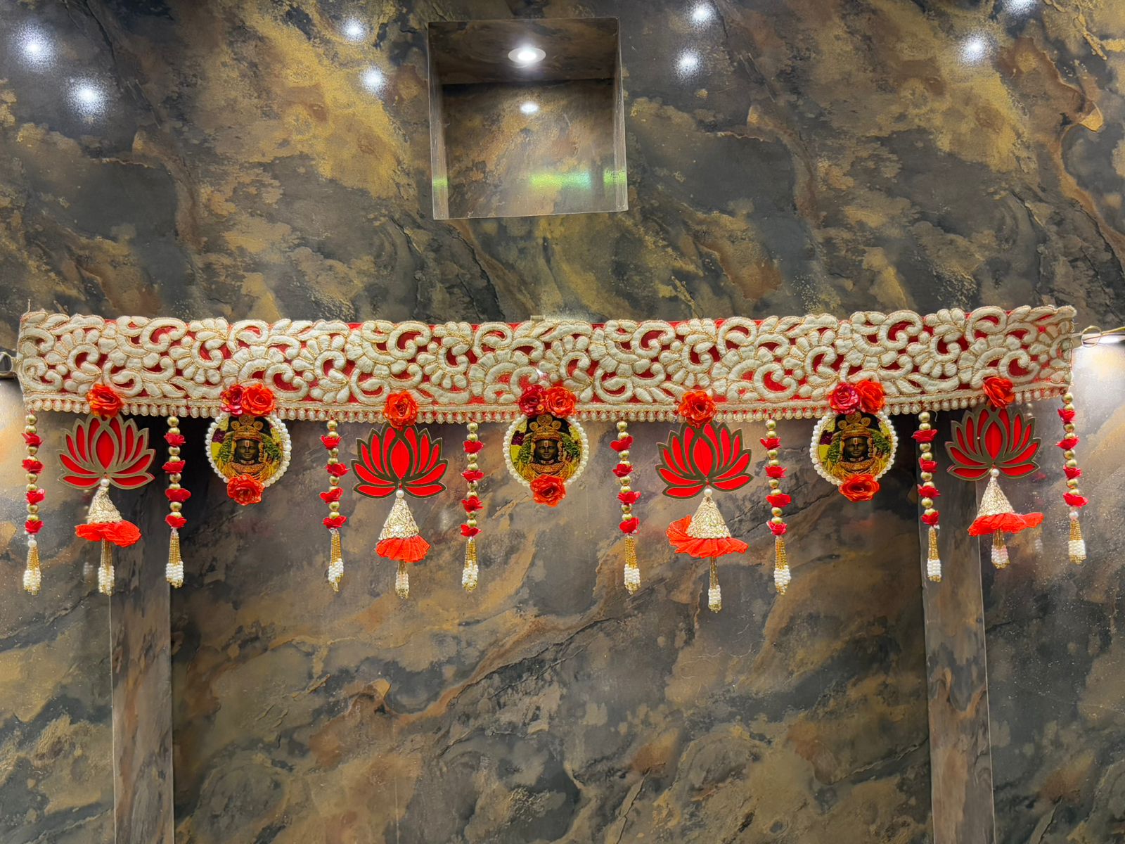 Decorative toran with red and gold elements on a marble design entrance.